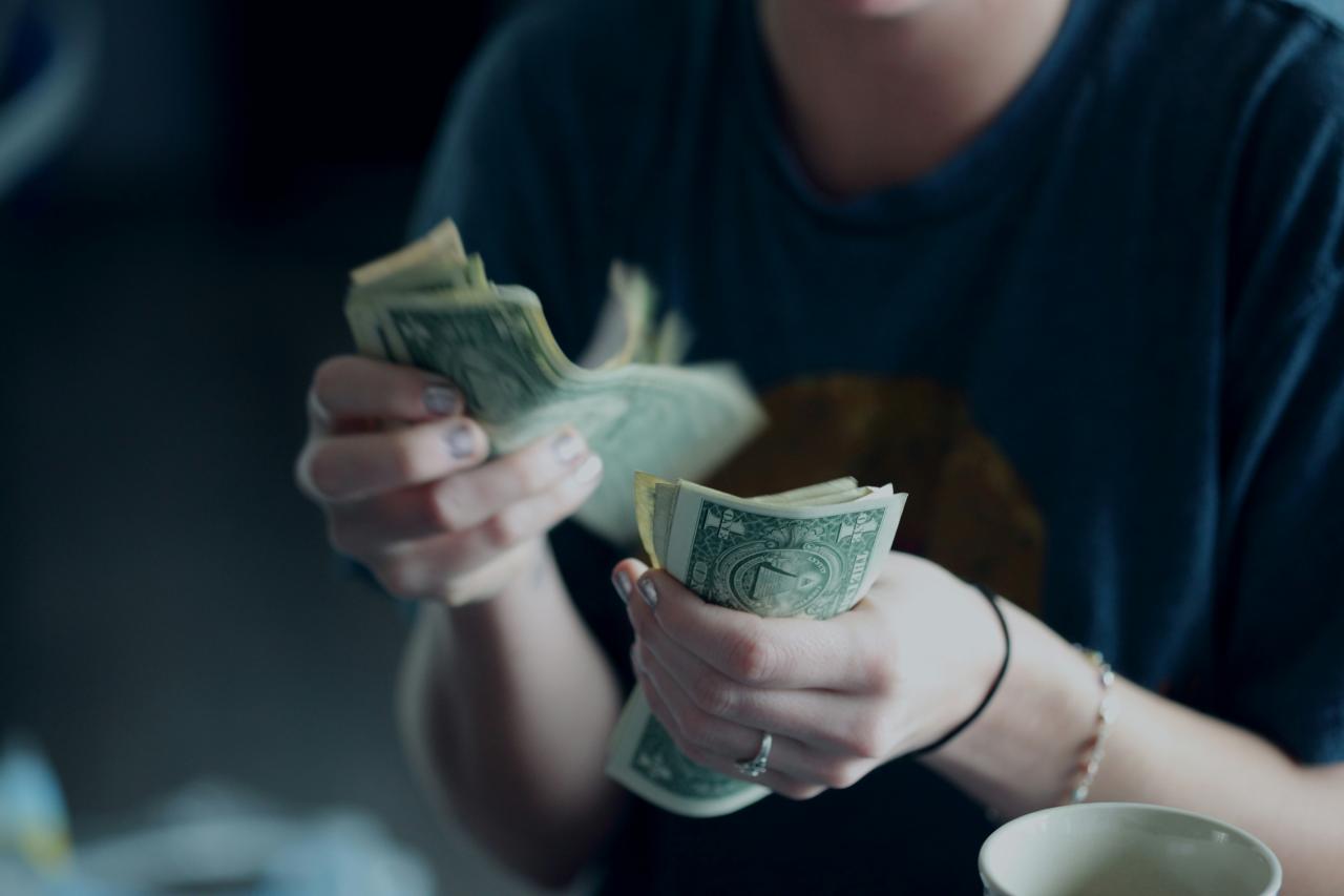 Fotografi fokus orang yang menghitung uang kertas dolar